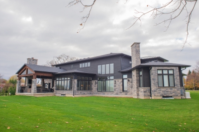 Designs by Santy :: Regal Prairie Estate Rear exterior with stone, black siding, and covered patio